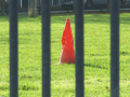Red bollard on grass behind fence