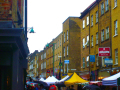 Sunday market on Brick Lane. There are stalls and many people. 
