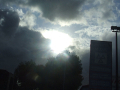 Sun breaking through clouds over park