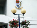 Lamp post with hanging baskets underneath crest	