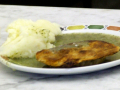 A plate of pie and mash potato in parsley liquor